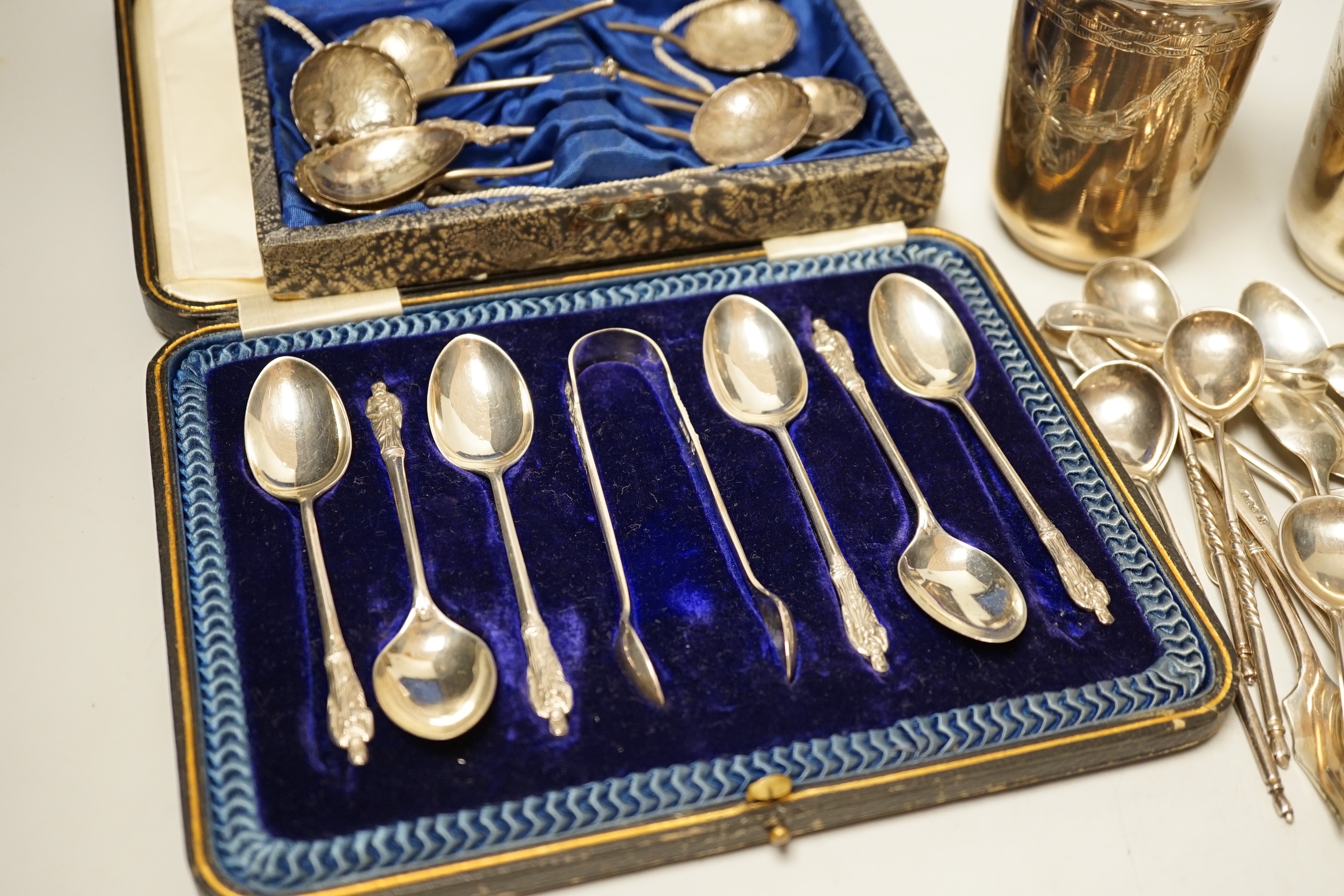 A pair of engraved white metal tumblers, stamped 'K980', four Russian 84 zolotnik spoon, a cased set of silver silver teaspoons with tongs, two silver napkin rings and other minor silver and white metal flatware.